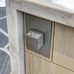 an electrical outlet is attached to the side of a counter top with marble and wood