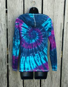 a blue and purple tie - dyed shirt hanging on a wooden fence