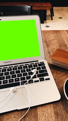 an open laptop computer sitting on top of a wooden table next to a cup of coffee