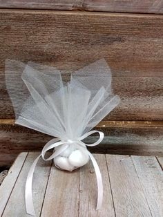 an egg in a net bag sitting on top of a wooden table next to a white ribbon