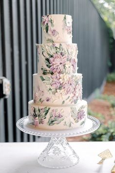 a three tiered wedding cake with pink flowers on it sitting on top of a glass plate