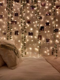 there is a bed with white sheets and lights on the wall