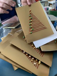 a person is making christmas cards out of brown paper and beaded with green beads