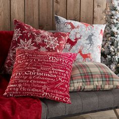 a couch with christmas pillows on it and a christmas tree in the backgroun