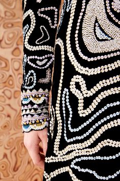 a close up of a person wearing a black dress with white and blue beads on it