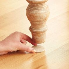 a hand is pushing a piece of wood on top of a table