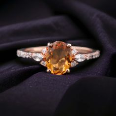 an orange sapphire and diamond ring on a black cloth