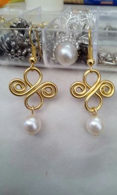 two pairs of earrings with pearls and gold wire on top of a white cloth covered table