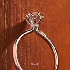 a close up of a diamond ring on a wooden surface with the word dicaco written below it