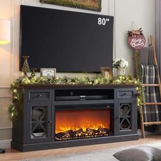 an entertainment center with a fireplace and christmas decorations on the mantle, in front of a flat screen tv