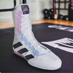 a pair of white and pink shoes sitting on top of a black mat in a gym