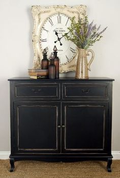 a black cabinet with flowers and vases on top in front of a clock that reads riverbend home