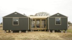 two tiny houses sitting in the middle of a field with ladders leading to them