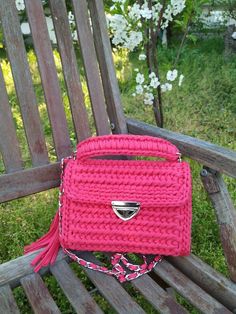 a pink purse sitting on top of a wooden bench