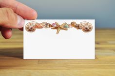 a hand holding a card with seashells and starfish on it