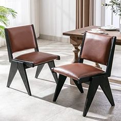 two brown leather chairs sitting next to each other on a white tile floor in front of a wooden table