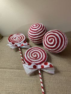 three red and white lollipops sitting on top of a couch next to each other