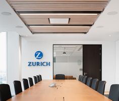 an empty conference room with black chairs and a large wooden table in front of it