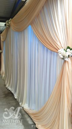 an image of a wedding backdrop with flowers on the top and drapes at the bottom