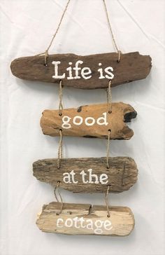 driftwood sign with words life is good at the cottage hanging on a white wall