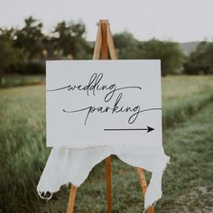 an easel with a sign that says wedding parking on it in the middle of a field