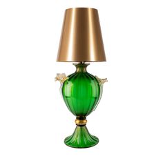 a green glass lamp with a gold shade on the base and a white flower in the middle