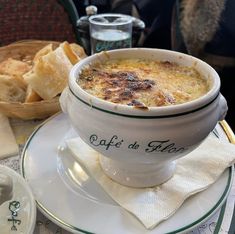 there is a bowl of soup on the table with bread in the basket behind it