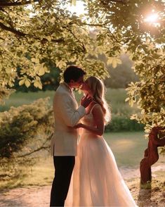 a bride and groom standing under a tree in front of the sun shining down on them