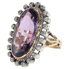 This circa 1890s ring features an impressive oblong oval-shaped 11 carat amethyst with excellent purple and rose coloring. The 23.63mm x 11.33mm is surrounded by a halo of 22 tiny European-cut diamonds, each set into its own silver collet. Together the diamonds weigh approximately .50 carats -but it's impossible to achieve an accurate carat total for the diamonds because of the mounting. The total dimensions of the face of the ring including the diamond surround would be 31.82mm x 19.35. And it Ruby Jewelry Ring, Rose Coloring, Antique Cocktail Ring, Victorian Diamond Ring, Amethyst And Diamond Ring, Pearl And Diamond Ring, Platinum Diamond Rings, Gold Cocktail Ring, Diamond Ring Settings