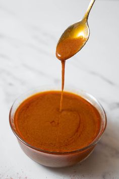 a spoon full of sauce being poured into a bowl