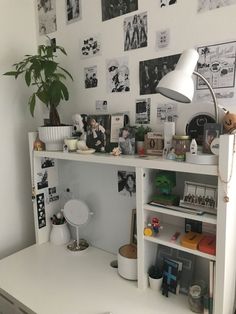 a white desk topped with lots of clutter next to a wall covered in pictures