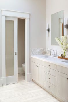 a white bathroom with double sinks and large mirrors on the wall next to each other