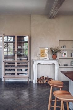 a kitchen with wood floors and white cabinets in the corner, along with a fireplace