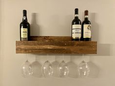 three wine glasses hanging from a wooden shelf