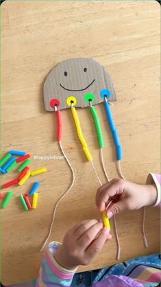 a child's hand holding an object made out of construction paper and plastic pegs