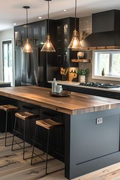 a large kitchen with black cabinets and wooden counter tops, along with bar stools