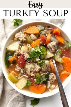 a white bowl filled with turkey and vegetable soup on top of a white tablecloth