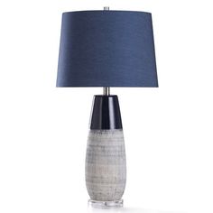 a table lamp with a blue shade on the base and a white vase underneath it