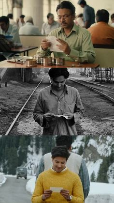 two people sitting at a table in front of a train track and another man standing next to them