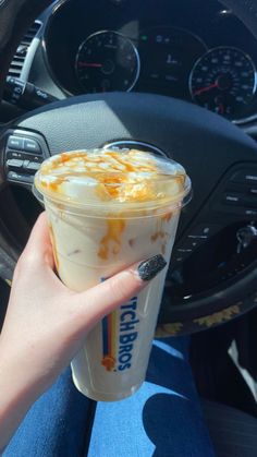 a person is holding up a drink in their hand while sitting in the driver's seat