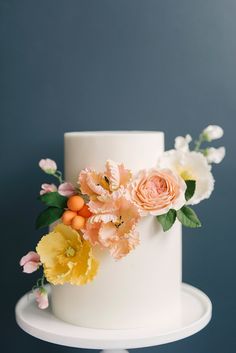 a white cake topped with flowers and greenery