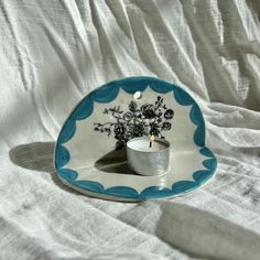 a blue and white plate with a flower arrangement on it, sitting on a bed