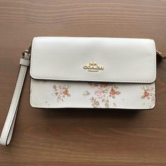 Like New, Never Used. No Tags Floral Design. Details Signature Coated Canvas & Smooth Leather One Credit Card Slots Snap Closure Fabric Lining Outside Zip Pocket Detachable Wrist Strap 7" (L) X 4" (H) X 1 3/4" (W) White Rectangular Coach Clutch, White Clutch Wristlet With Removable Pouch, Elegant Cream Bag With Wrist Strap, Coach Clutch Wristlet With Removable Pouch, Cream Clutch Bag With Wrist Strap, Cream Clutch With Wrist Strap, Elegant White Coach Wristlet, Coach Rectangular Clutch With Detachable Strap, Coach Clutch With Detachable Strap, Rectangular