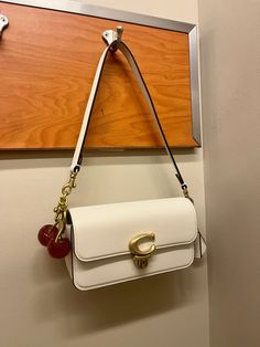 COACH Studio Baguette in Chalk with gold hardware. Cherry charm attached. Love!!!! Coach Baguette Bag, Studio Baguette Bag Coach, Coach Mini Bag, Cute Coach Bags, Coach Bags Handbags, Coach Bags Aesthetic, Coach Bag With Cherry Charm, Tas Coach, Coach Purse