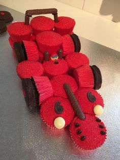 a car made out of red cupcakes with chocolate wheels and eyes on it