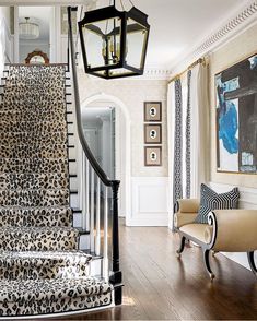 a leopard print carpeted staircase leading up to the second floor in a home with white walls and wood floors