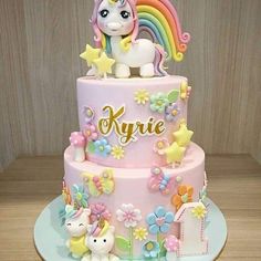 a pink cake with a rainbow horse and stars on the top is sitting on a table