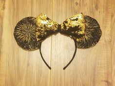 a mouse ears with gold sequins is on a wooden surface and looks like it has been made out of wood