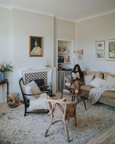 a woman sitting on a couch in a living room next to a table and chair