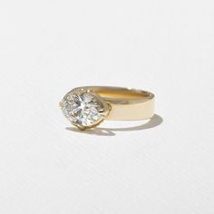 a yellow gold ring with a single diamond in the center on a plain white surface